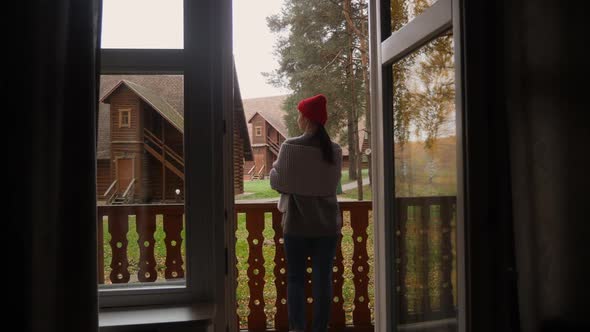 Woman in a Knitted Red Hat and Scarf Drinks Hot Tea Standing alt