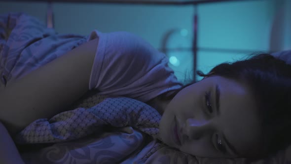 A Young Woman Lies in Bed at Night and Cannot Sleep. Millennial Woman have trouble sleeping alt