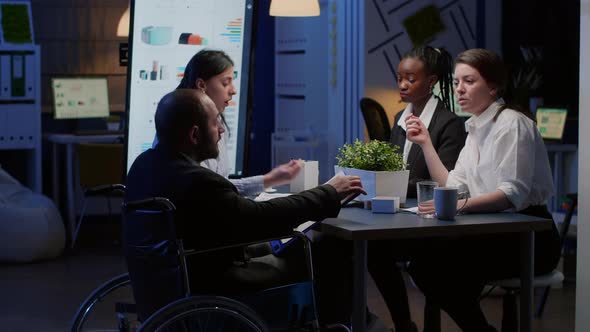 Paralyzed Businessman in Wheelchair is Ignored While Working in Business Office Meeting Room alt