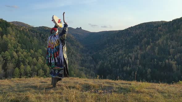 Siberian Shaman Performs a Ritual Dance and Beats a Tambourine on the Top of the Mountain.