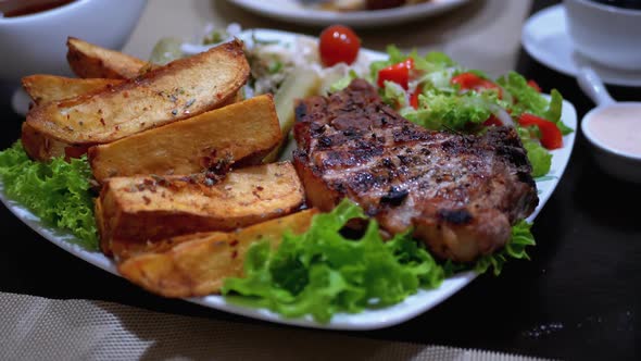 Steak on Ribs with Potatoes and Salad on a Table in a Georgian Restaurant alt