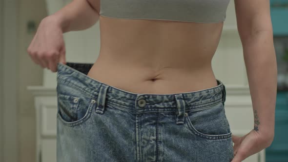 Close Up of Woman Wearing Oversized Jeans After Weight Loss alt