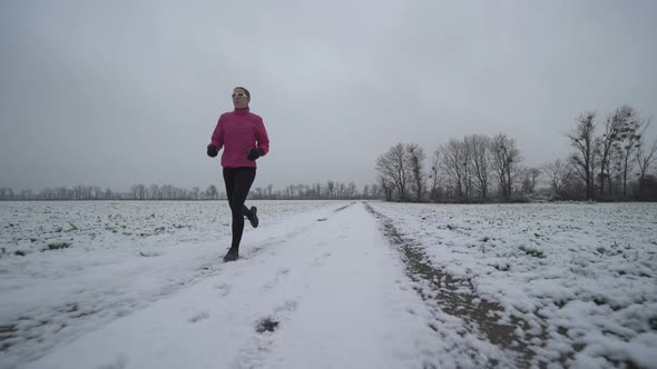 Woman Jogging Alone on Winter Day on Open Fields