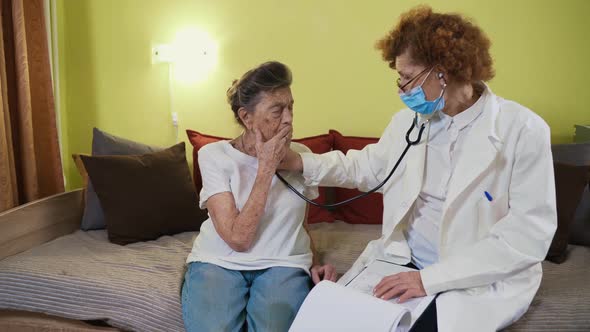 Elderly Caucasian Woman Doctor Listening To Elderly Patient Breathing Medical Exam with Stethoscope alt