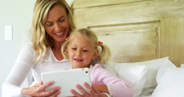 Mother and daughter using digital tablet in bedroom at home 4k