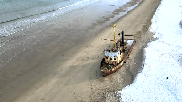 Aerial Top View of Old Wrecked Fishing Ships Drowned at the Sea Shore in Snowy Winter Season alt