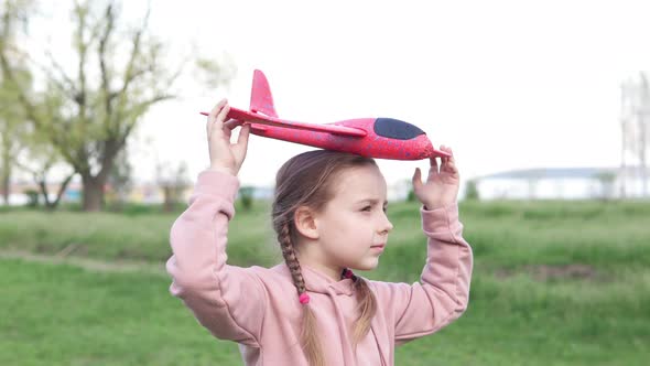A girl in the park plays with a toy plane, she wants to become an astronaut. Dreamer pilot. alt