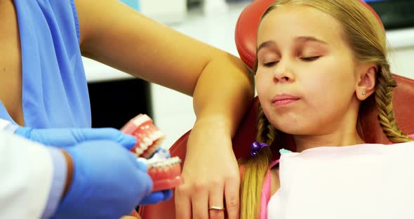 Dentist showing young patient how to brush teeth alt