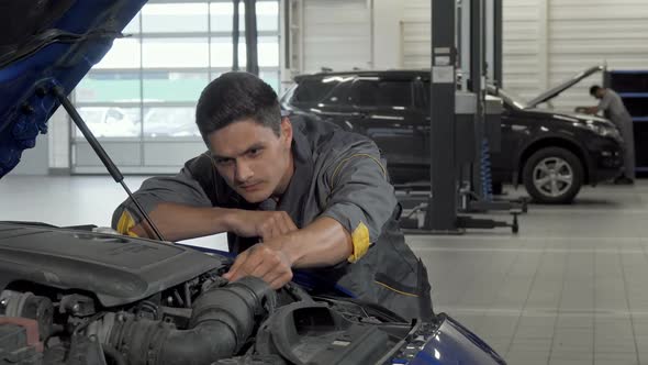 Auto Mechanic Looking Under the Hood of a Car at the Garage