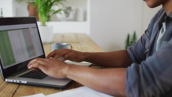 African american man working from home and using laptop alt