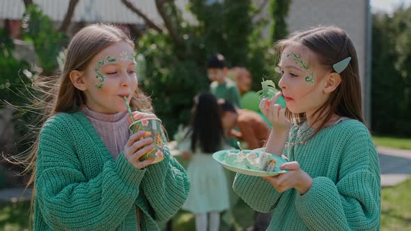 Two Girls Drinking and Eating at the Backyard Party on a Sunny Day