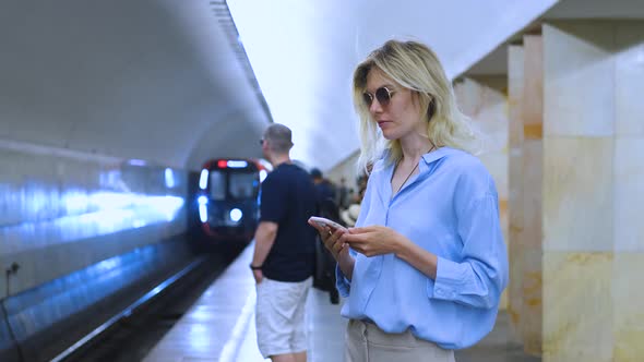 portrait of a woman with a phone and an arriving subway train