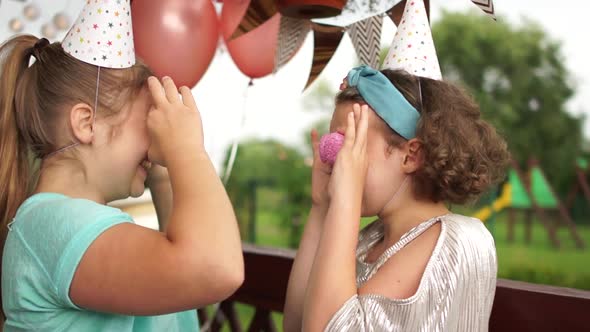 Crazy Cheerful Girls in Birthday Hats Smiling, Having Fun and Looking Through Two Pink Cookies on alt