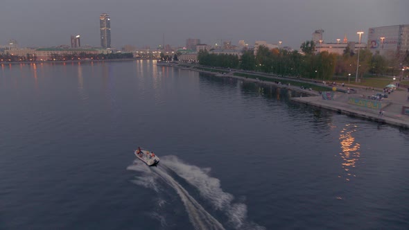 An Aerial View of a Boat That Floats on a River in the City Centre at Sunset alt