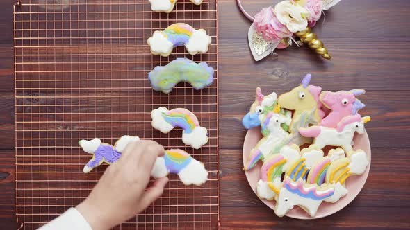 Unicorn cookies decorated with royal icing drying on drying rack. alt
