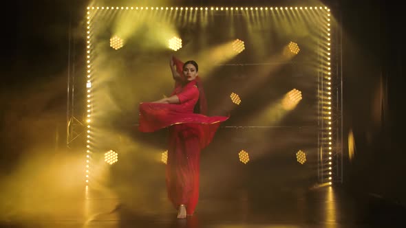 A Young Girl Dancer in a Red Sari, Indian Folk Dance, Shot in a Dark Studio with Smoke and Yellow alt