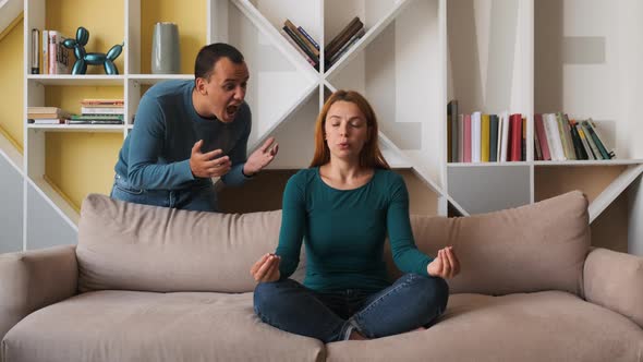 Desperate Girlfriend Meditating Sitting on Sofa While Boyfriend Screams Accusing Her  alt