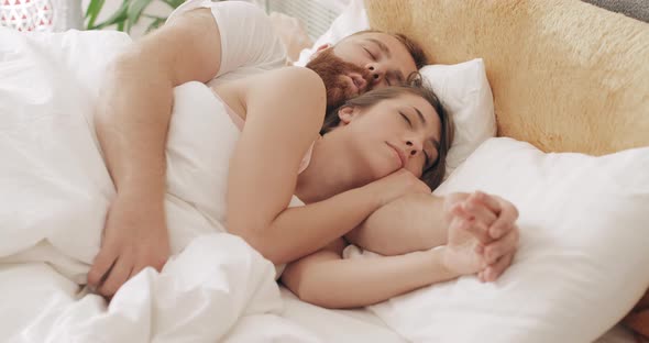 Portrait of Cute Loving Couple Embracing in Bed While Sleeping in Early Morning. Handsome Man alt