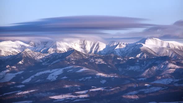 Snowy mountain peaks. The clouds spill over the mountain tops. Winter  landscape alt