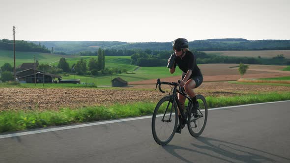 Sportive fit female cyclist drinking water or isotonic during intense cycling training alt