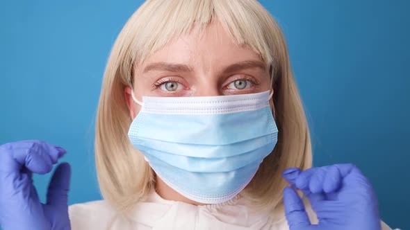 Young Female Doctor or Nurse in Protective Suit Medical Mask Gloves Putting Mask on Her Face for alt