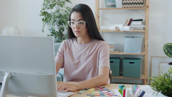 Portrait of Serious Asian Girl Creative Designer Working with Computer Typing Looking at Color alt