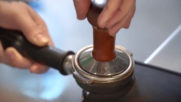 Preparing ground coffee by tamping fresh coffee.