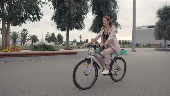 Young Townswoman Is Riding Bike in City in Summer Day View on Her Face alt