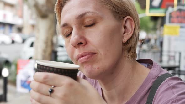 An Adult Caucasian Woman Drinks a Hot Drink and Closes Her Eyes with Pleasure and Makes a Wish