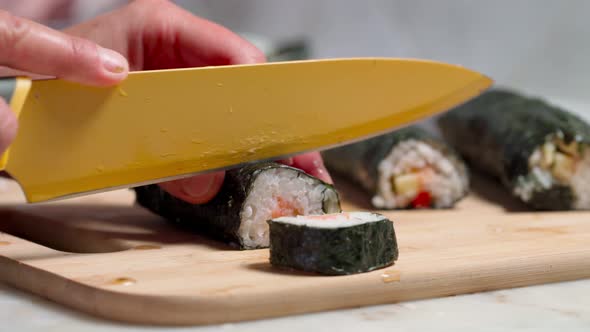 The Chef Cuts Sushi and Rolls Made From Seafood with Asian Ingredients with a Knife alt