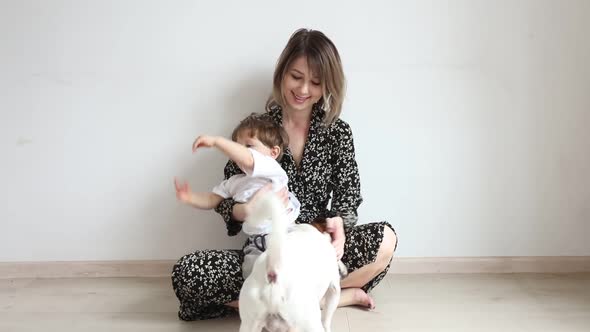 Mother with son and a dog sits on floor in home
