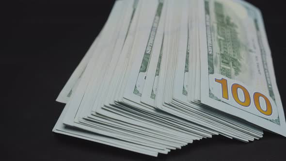 A Large Stack of Dollar Bills Rotates on a Black Background