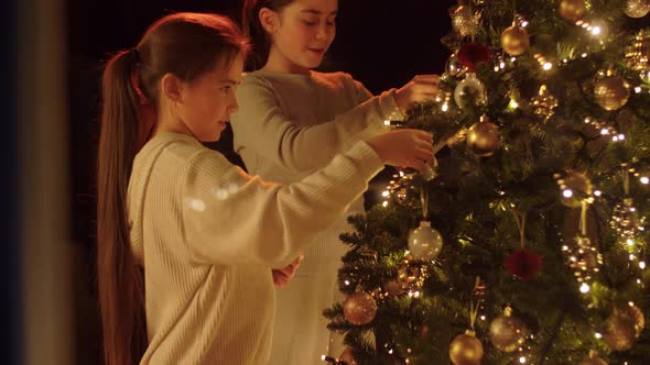 Happy Girls Decorating Christmas Tree at Home