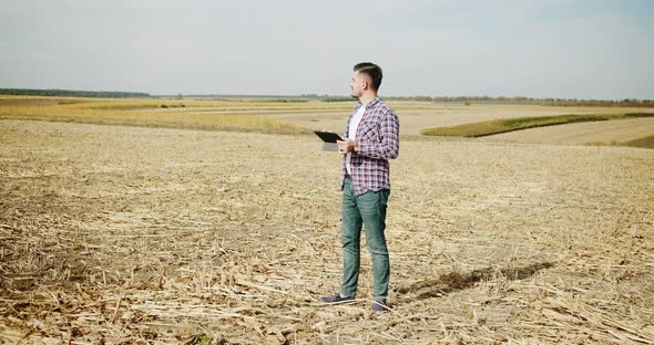 Young Farmer Stand on Field Agriculture and Use Digital Tablet alt