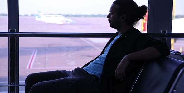 Young Man Waiting Flight In Airport alt