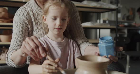 Grandmother Teaches Her Granddaughter Working on a Pottery Rotating Wheel