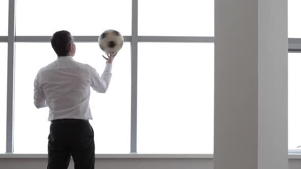 Businessman Plays with a Football Ball