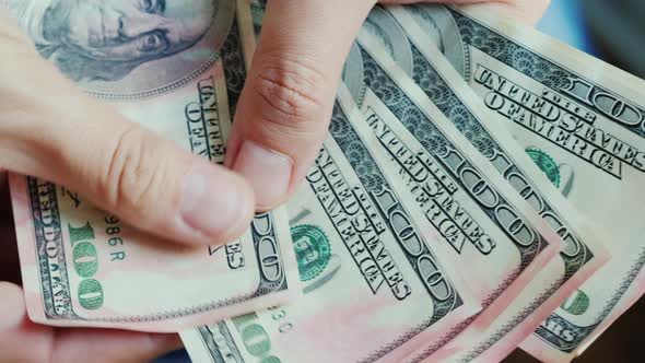 Men's Fingers Look at American Dollar Bills. Money Is Damaged By Pink Paint alt