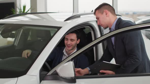 Car Sales Young Successful Man Talking to a Manager About Buying a New Automobile in an Auto Center