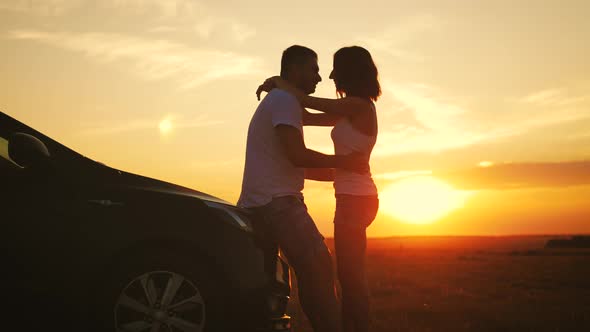 Beautiful Young Couple Standing Near Car on Sunset alt