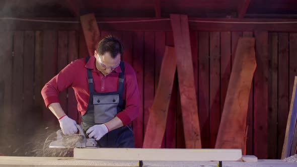Carpenter Polish the Surface of Wooden Blank with Planer and Flies Sawdust alt