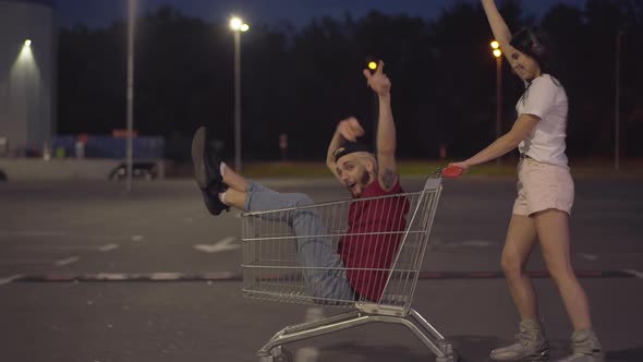 Side View of Carefree Woman on Skates Riding Trolley with Cheerful Man, Positive Joyful Caucasian alt