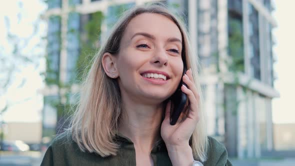 Beautiful Positive Blonde Woman Calling on Mobile Phone in the Street Outdoor alt