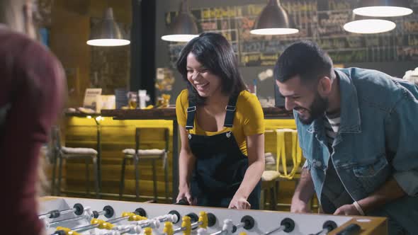 Laughing couple playing foosball with mates