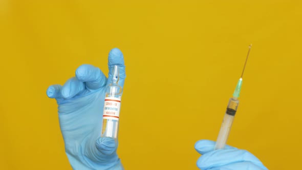 doctor's hands in gloves hold a coronavirus vaccine and a syringe with an injection alt