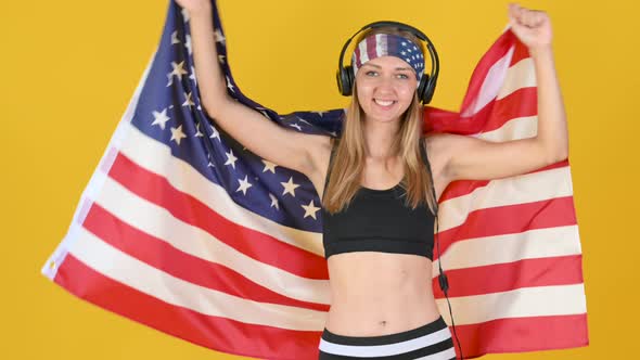 Happy Young Girl with Headphones Smiling and Waving American Flag