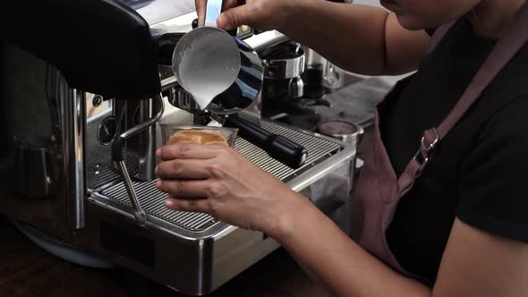Barista making Latte art with milk foam in tumbler glass