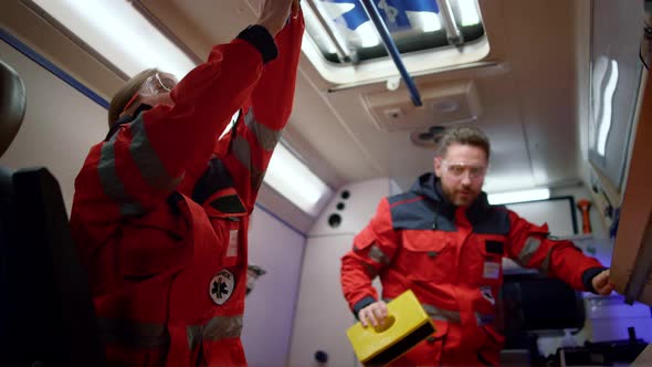 Paramedics Preparing Medical Equipment for First Aid in Ambulance Car alt