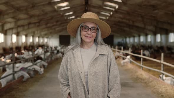 Smiling Senior Woman in Straw Hat Posing at Goat Farm alt