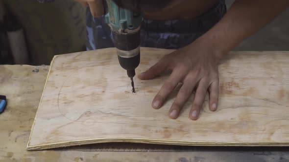 Caucasian male hands drilling into a curved wooden board. Slow motion alt